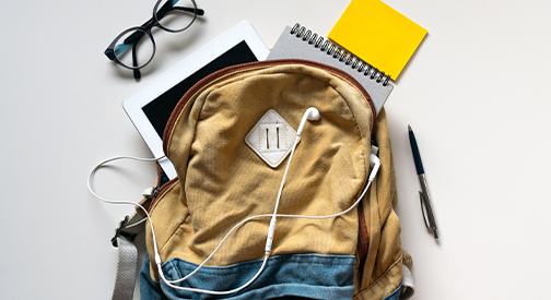 Backpack with earphones, notebook, tablet, glasses and a pen coming out of the top